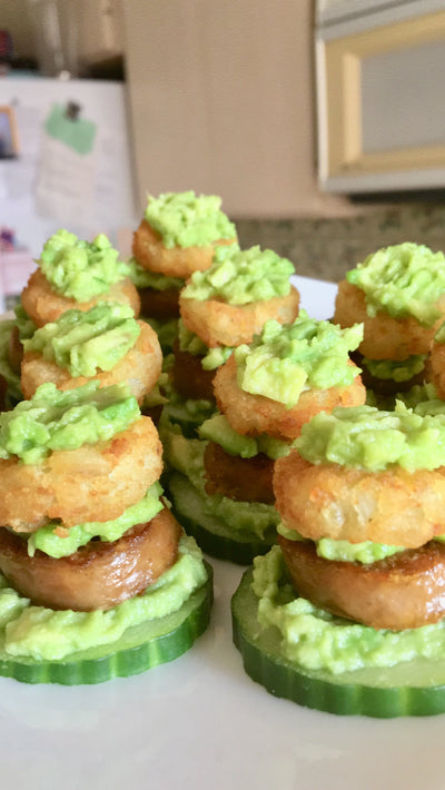 Stacked cucumbinis, cucumber slices topped with smashed avocado, Beyond sausage, and hashbrowns